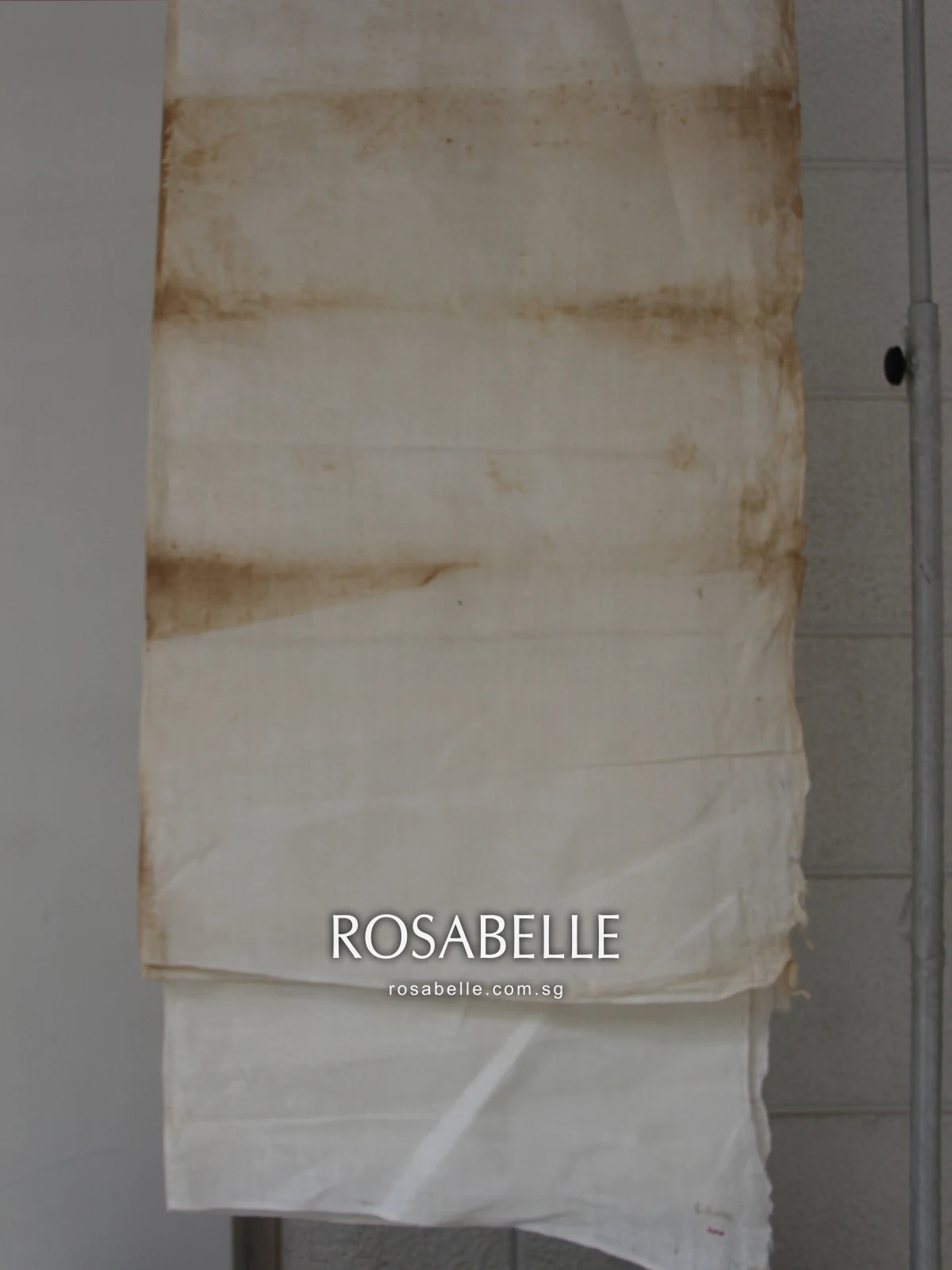 Long damask cloth hanging in folds, with bands of brown storage staining across each fold line