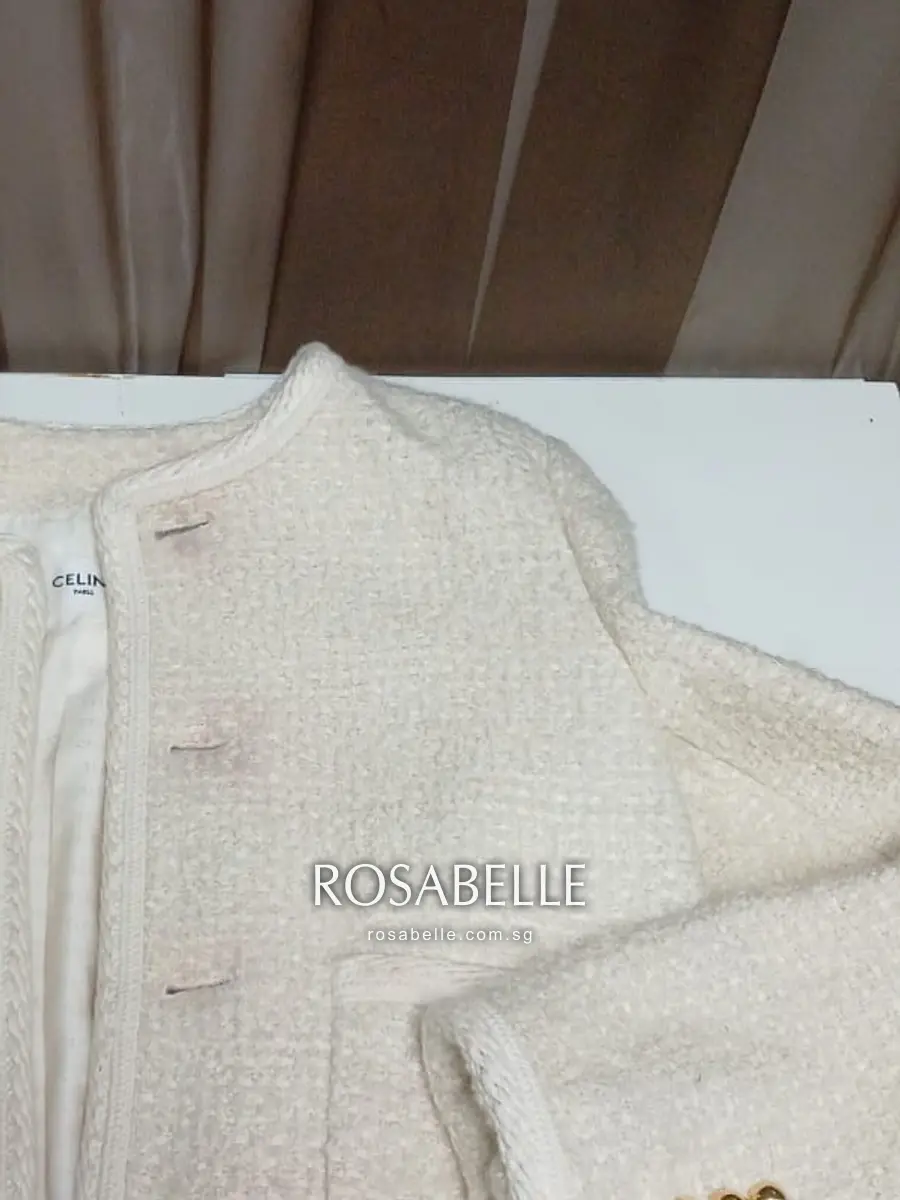 Close-up of pink dye transfer along the front placket of a cream bouclé jacket