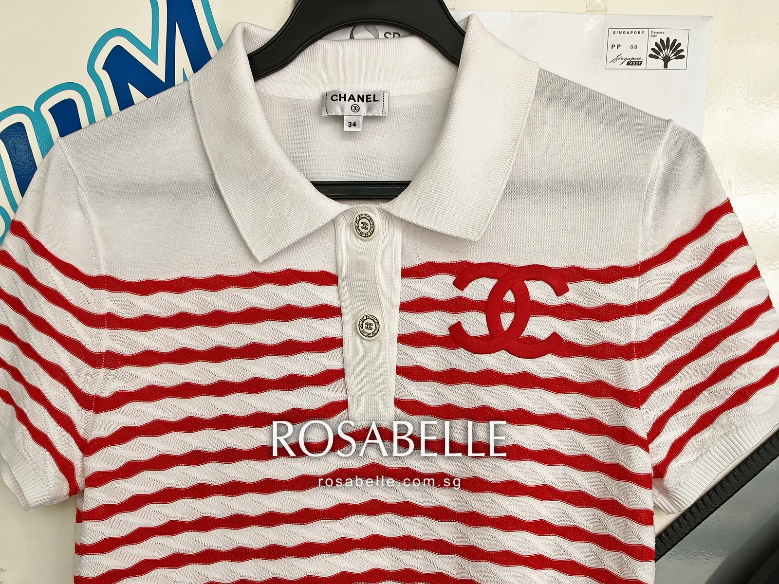The same Chanel polo on a hanger after cleaning, the white collar, button placket and red CC logo