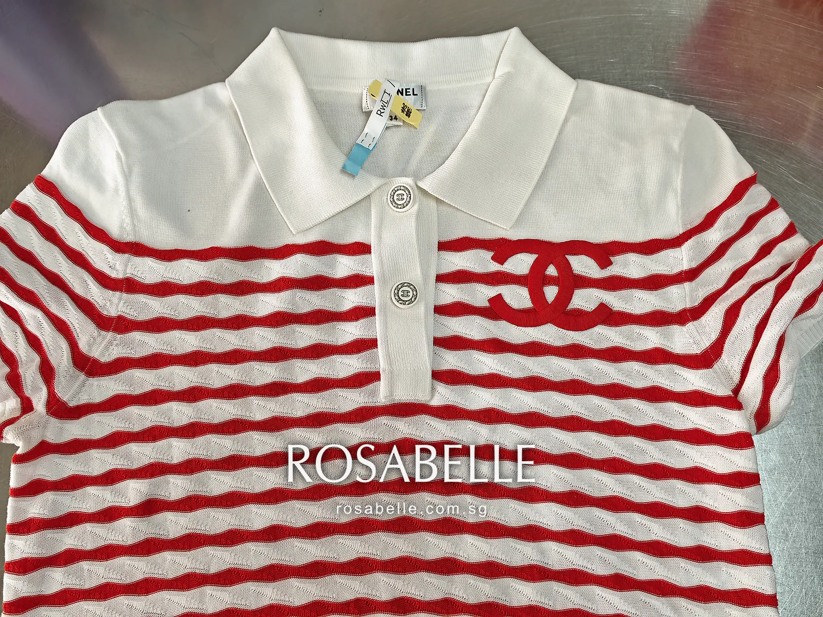 Front of the white and red striped Chanel knit polo laid flat, red CC logo on the chest and paper tags on the collar