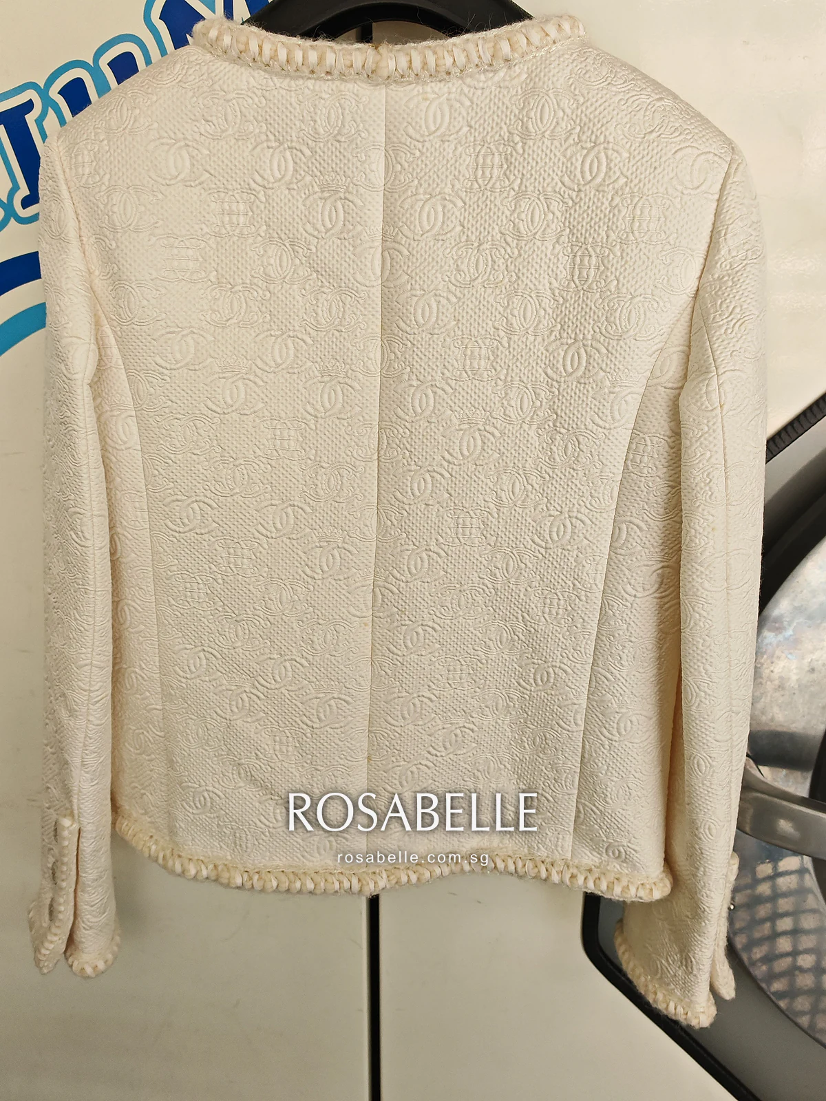 Back of the cream Chanel jacket on a hanger before cleaning, with light yellow spotting