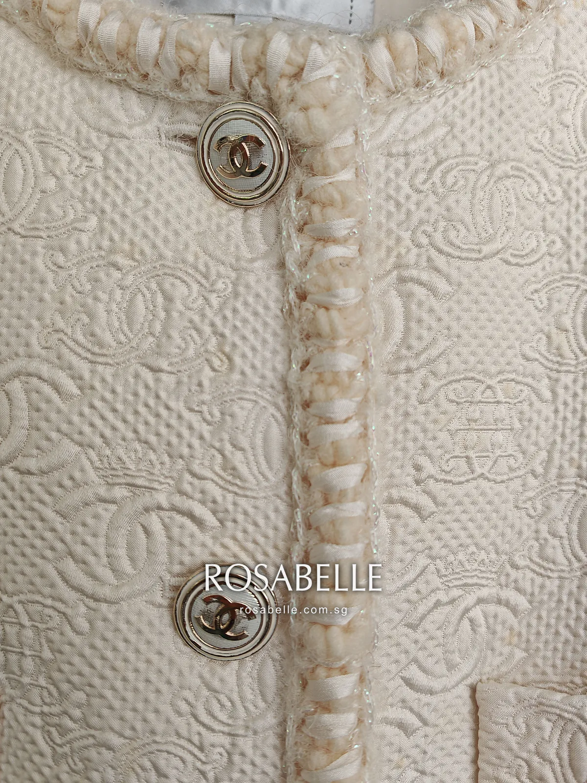 The same braided edge and gold CC buttons after cleaning, the braid still full and the cloth beside it clear