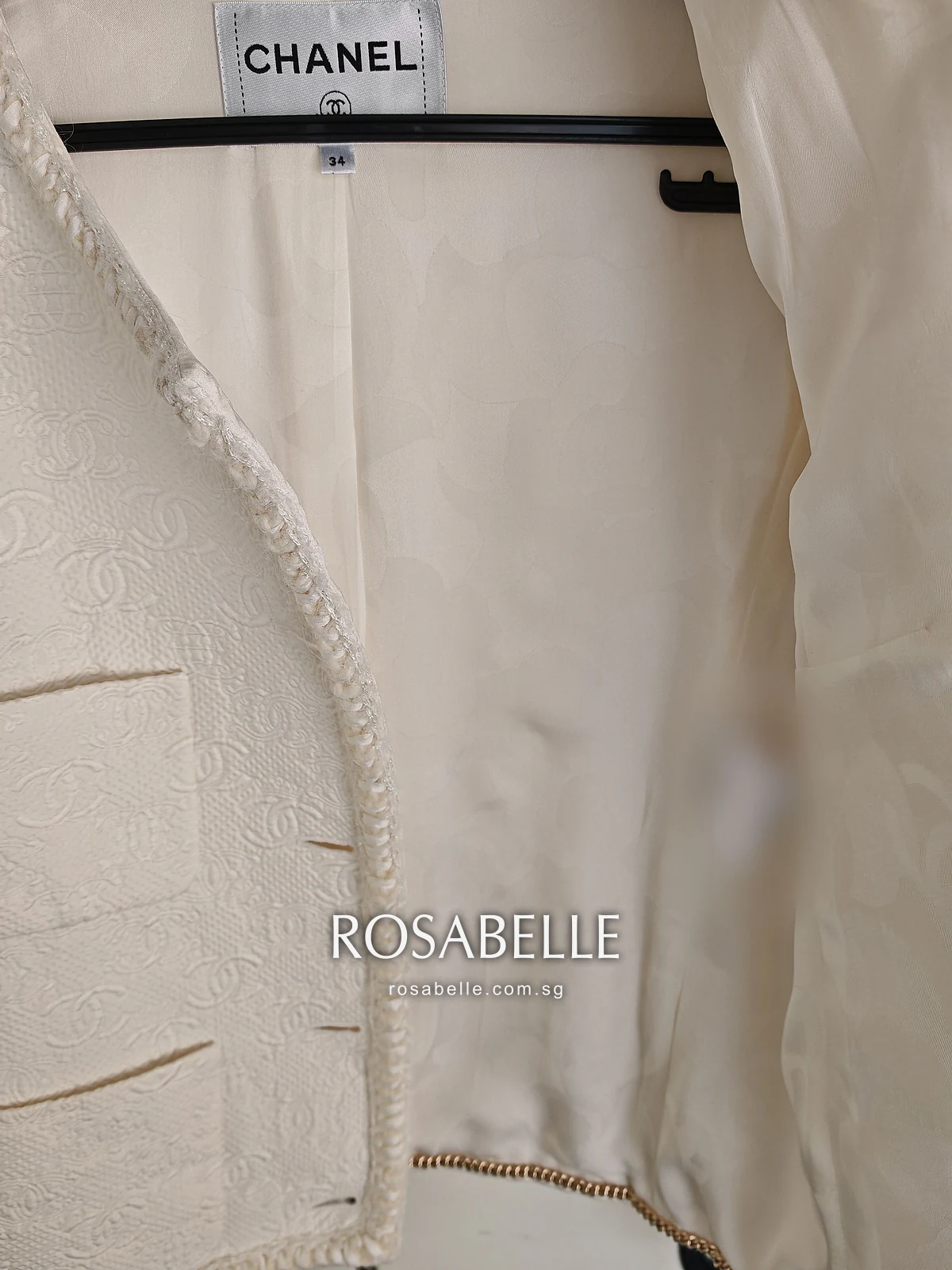 The jacket held open to show its cream silk lining, smooth below the CHANEL label after cleaning