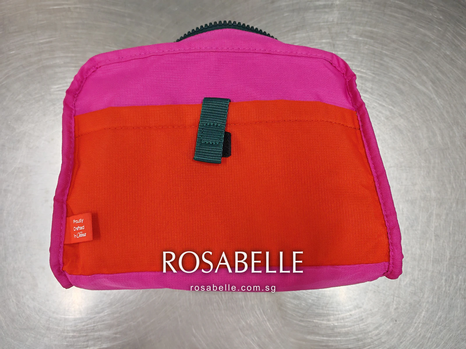 Orange slip pocket set into the pink lining, with a teal tab and a small orange woven label, before cleaning