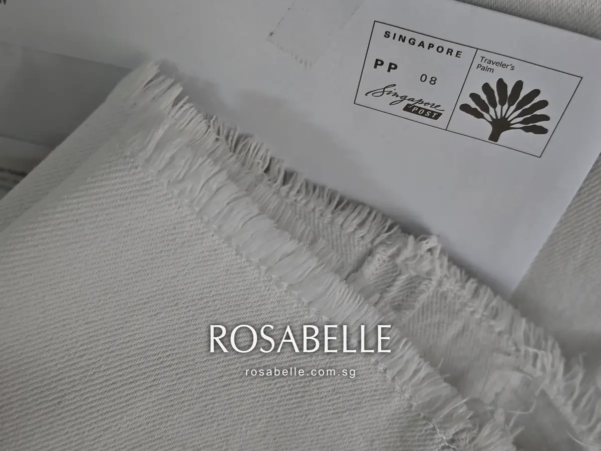 Frayed raw hem of the white jeans after cleaning, loose cotton threads lying on a white envelope