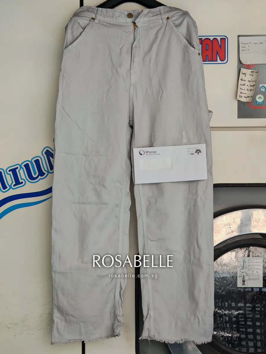 Wide-leg Darkpark jeans hanging in front of the shop machines, grey all over, a white envelope held against one leg