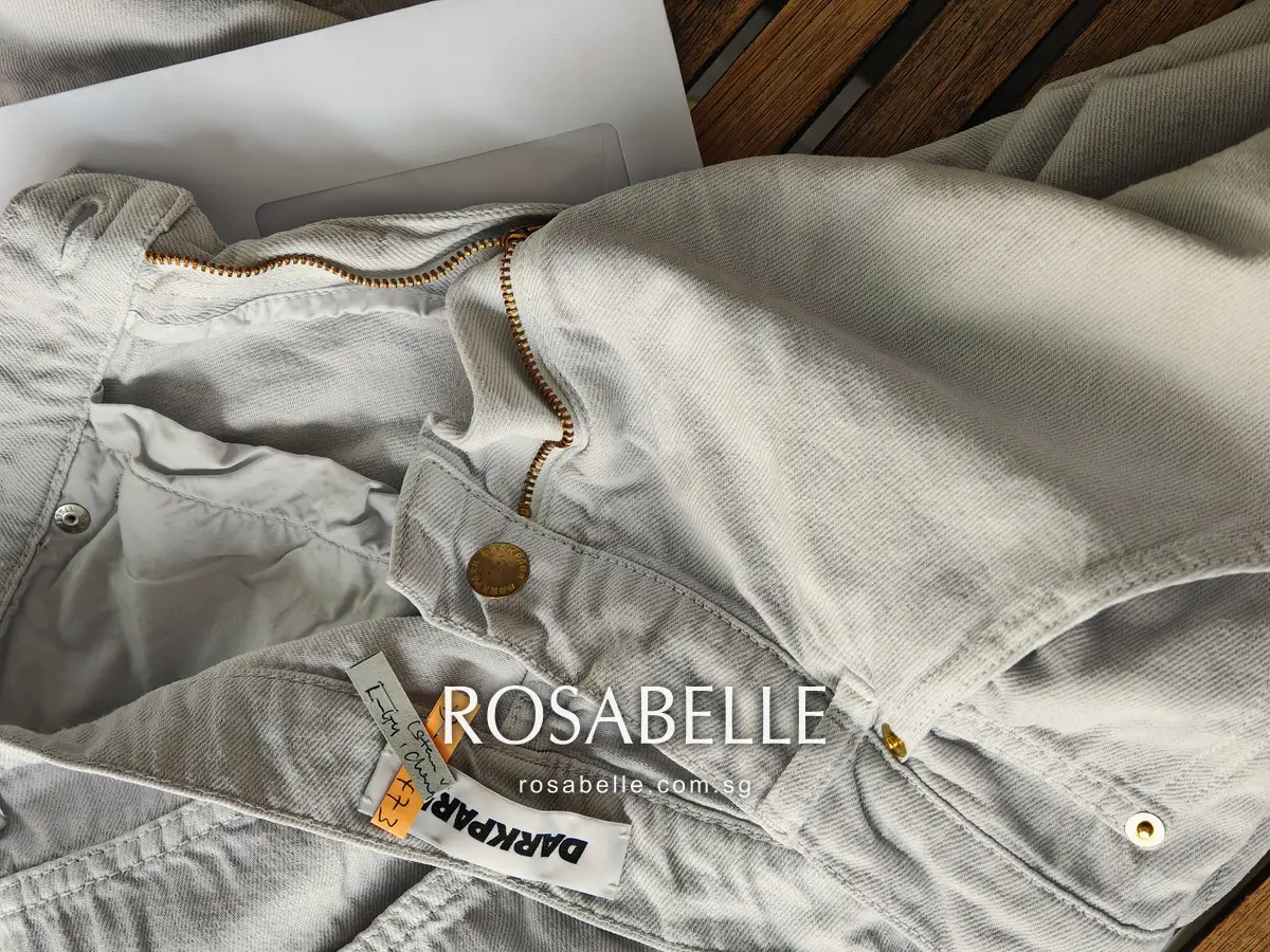 Open fly and inner waistband of the jeans, zip and brass rivets, the pocket linings as grey as the outer denim