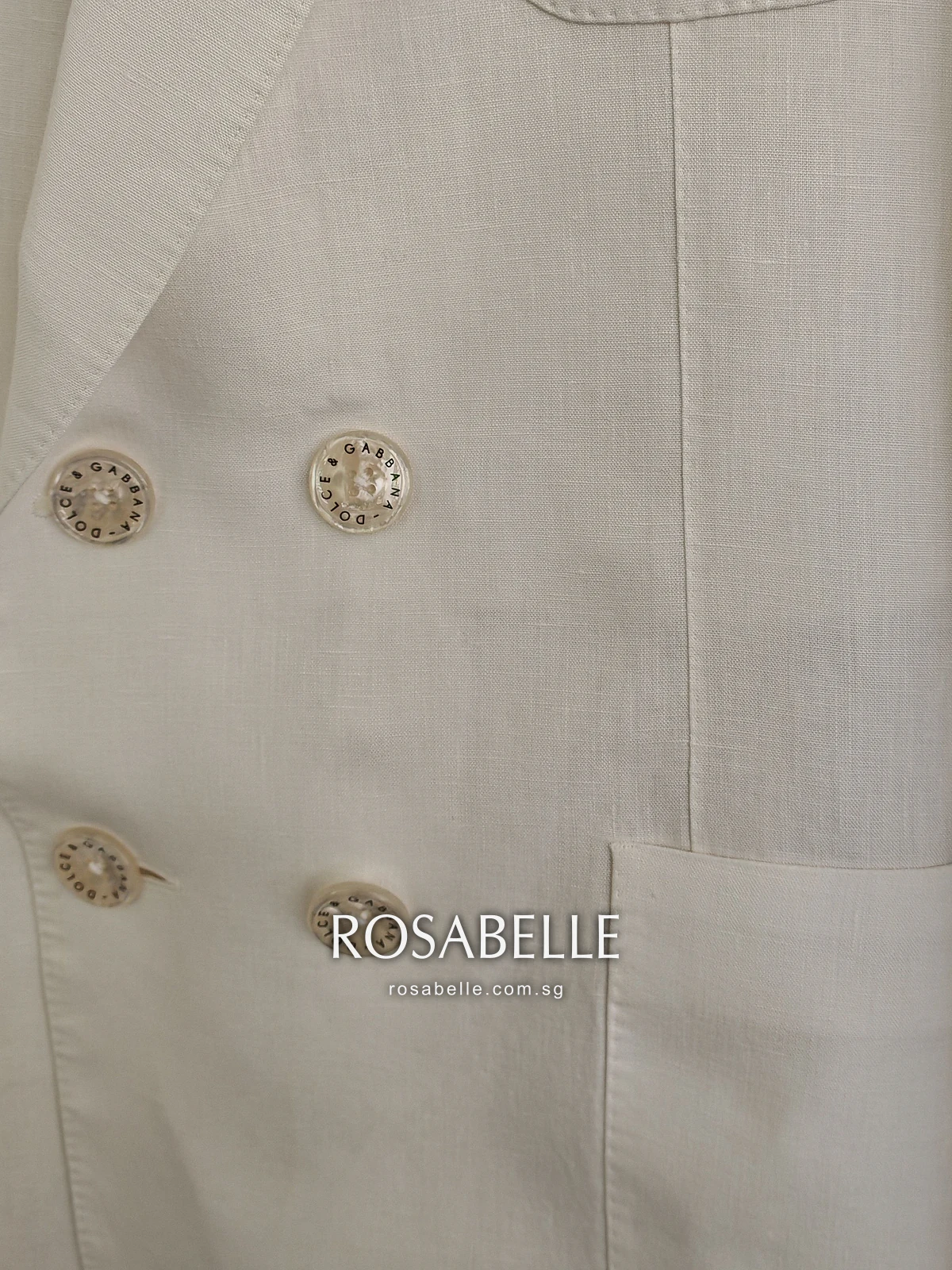 Lower front of the Dolce and Gabbana coat after cleaning, the patch pocket and double row of buttons on clean cream linen