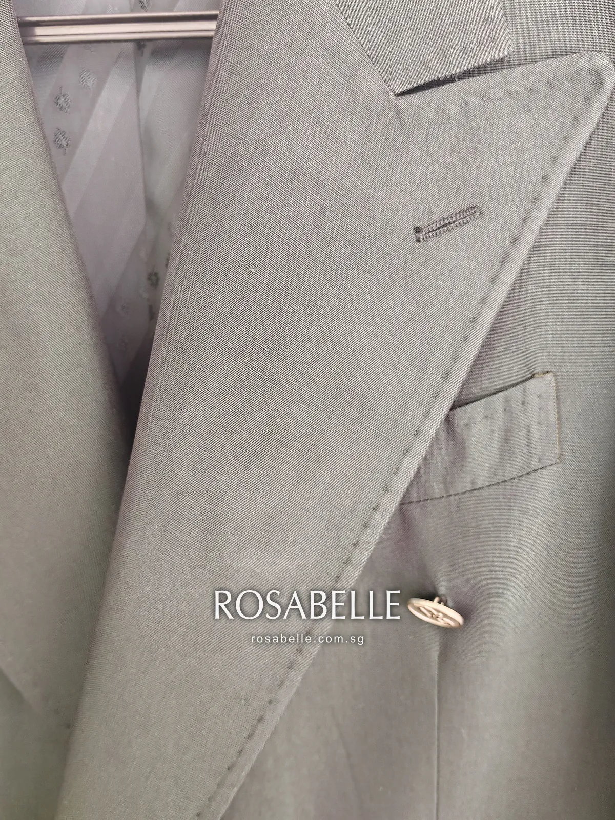 Close view of the green silk lapel after cleaning, its stitched edge and buttonhole lit from the side