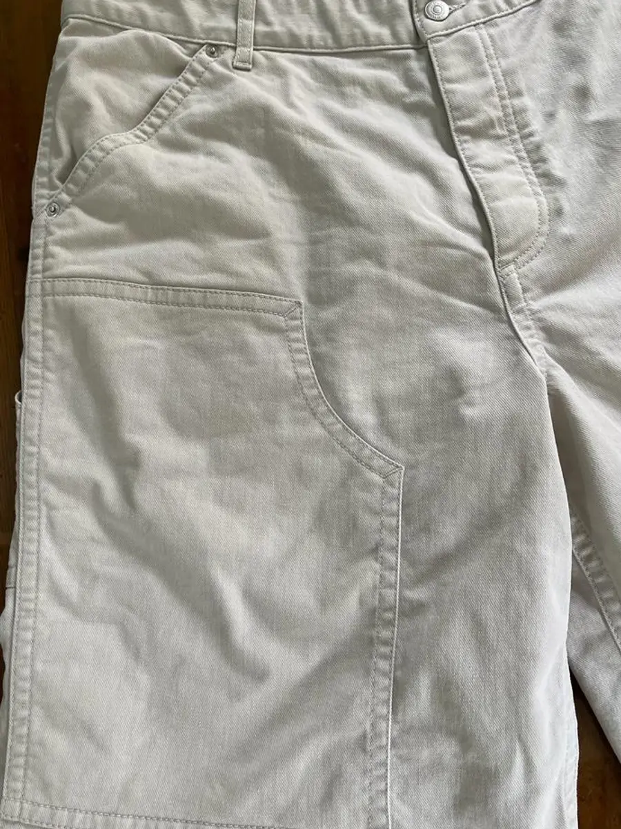 Close-up of the waistband and front pocket of the Dior Bermudas showing patchy grey discolouration in the cream twill before treatment