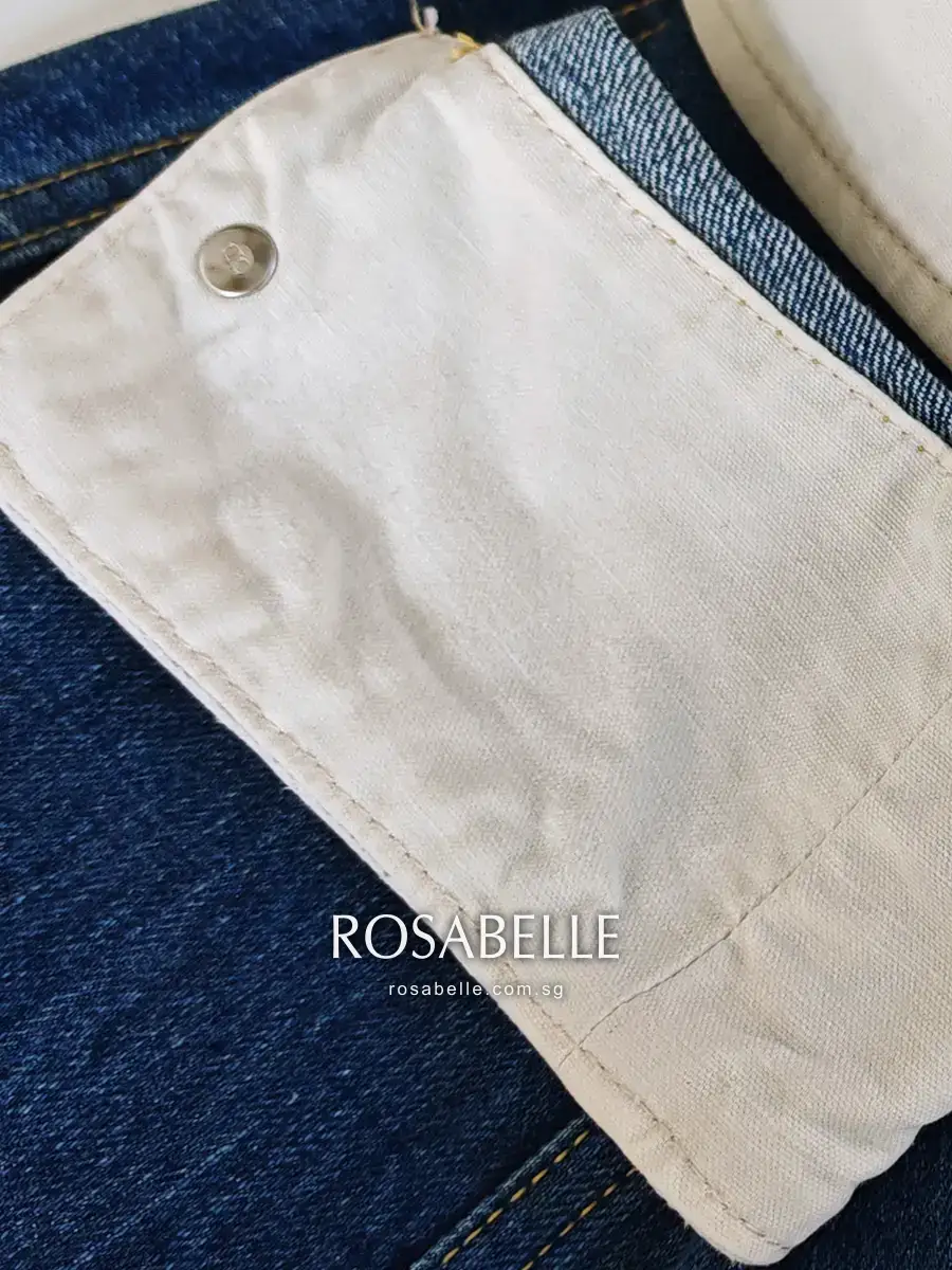A cleaned cuff facing on the Dior denim jacket, the cream cotton clear of speckling and warm cast, with the indigo denim beside it unchanged