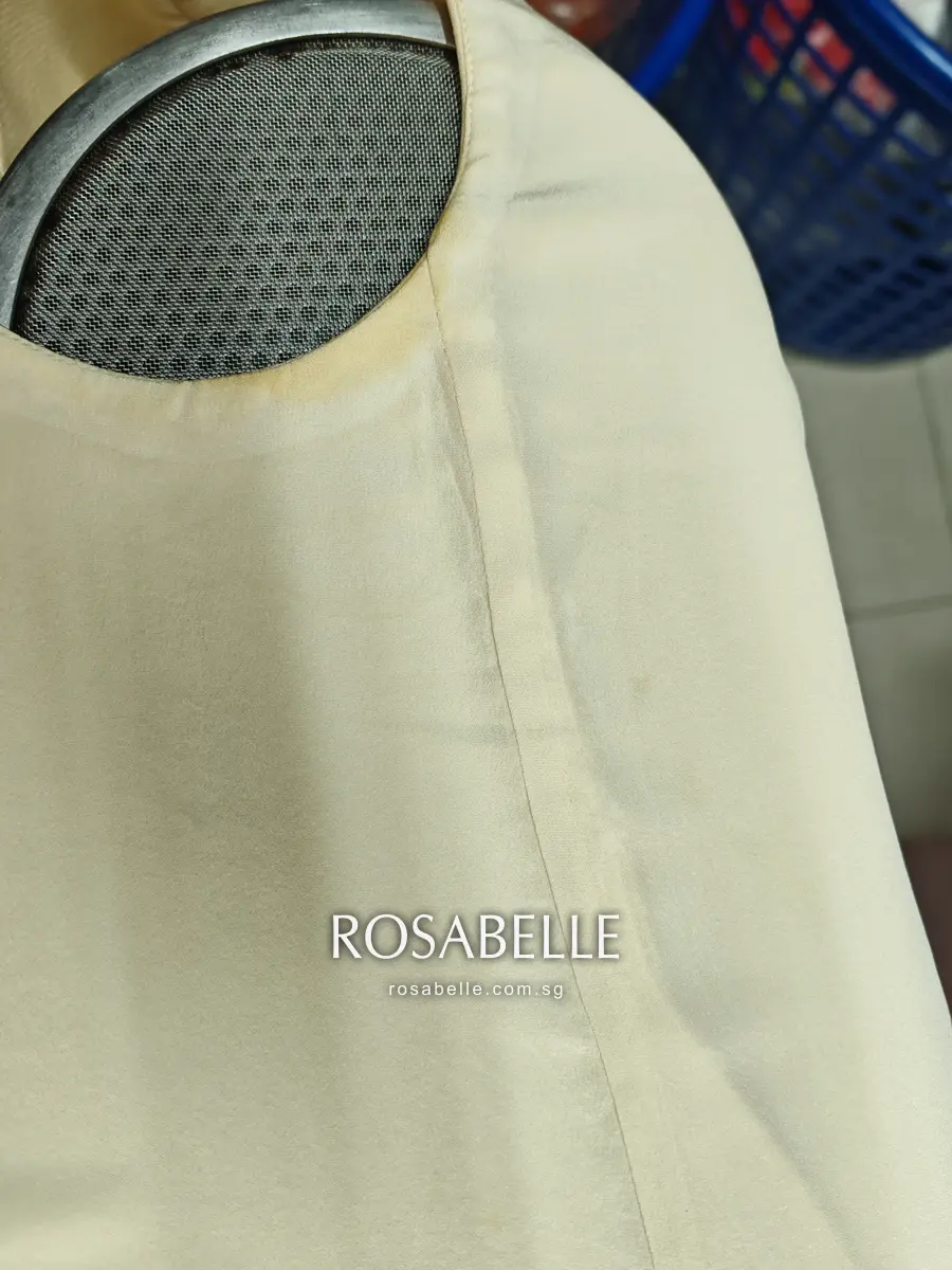 Close view of the dress armhole before cleaning, a yellow-brown ring along the seam where perspiration had set