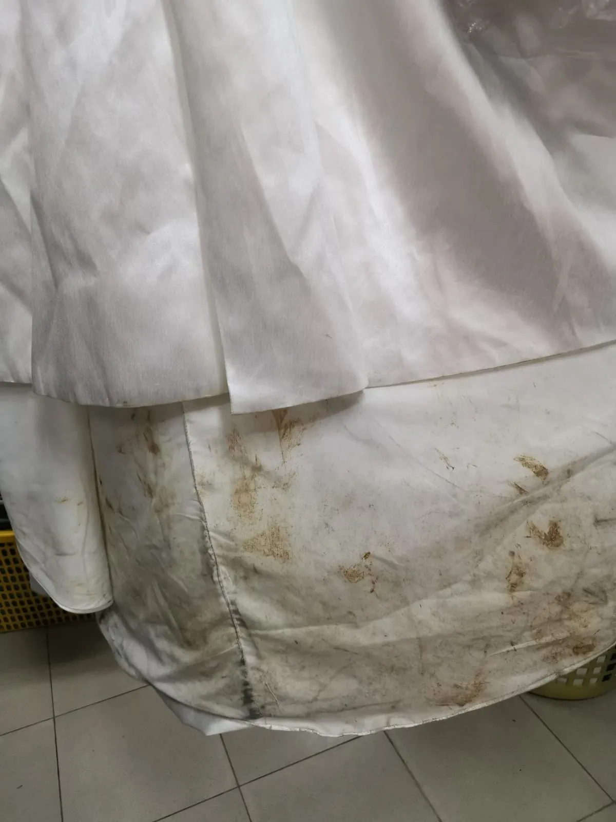 Close-up of mud stains ground into the hem and train of a wedding gown before restoration