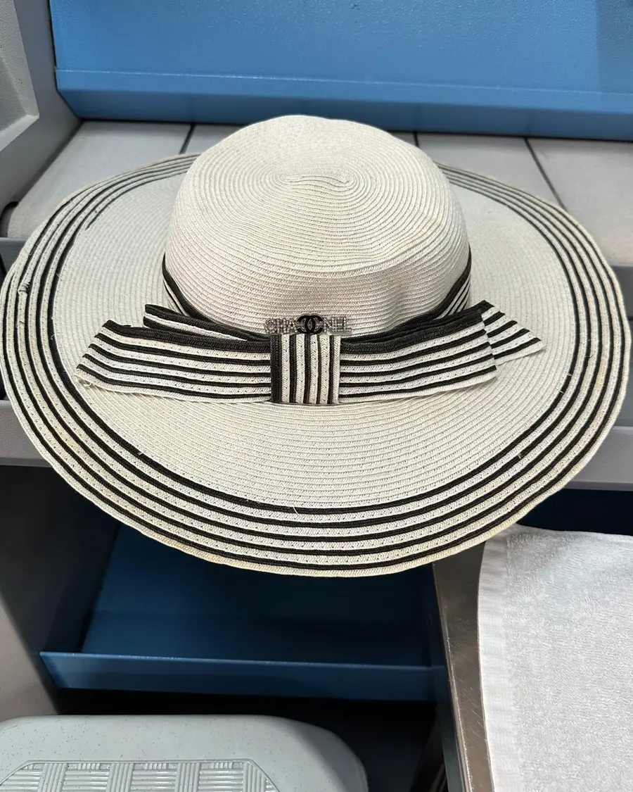 Wide-brimmed straw hat with a black and white striped band and bow, showing the fine braid construction, at Rosabelle Launderette Singapore