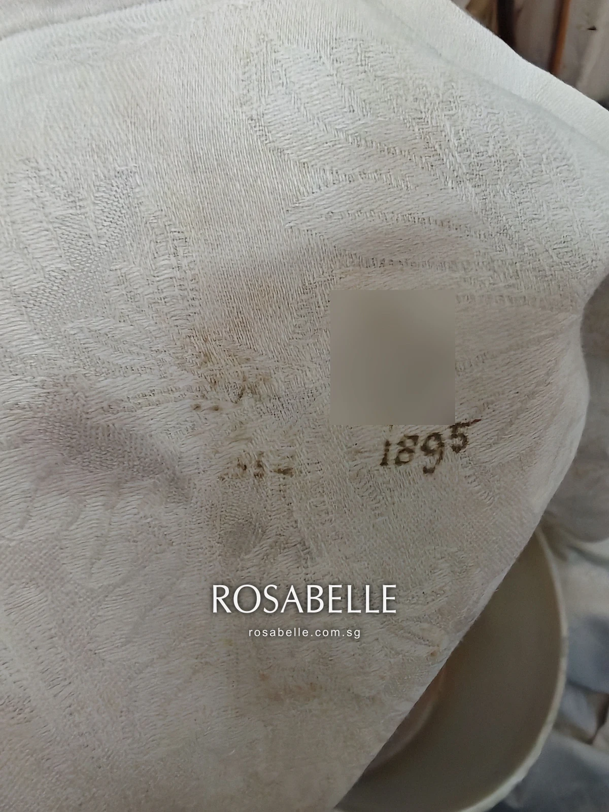 Cross-stitched monogram on damask linen with its initials blurred and the year 1895 left legible