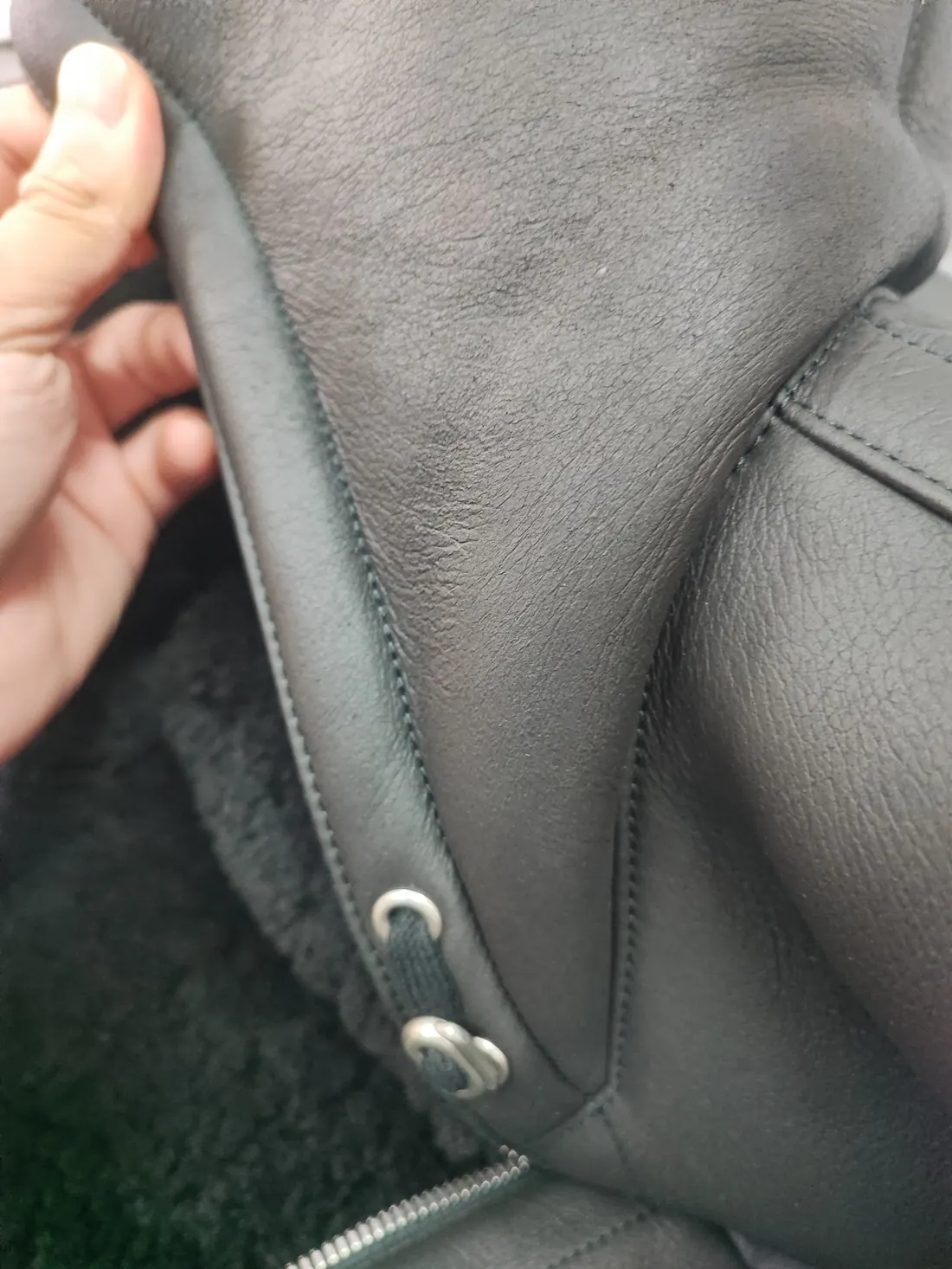Close inspection by hand of the Hermès shearling jacket's hide, hardware and seams during conditioning at Rosabelle Launderette