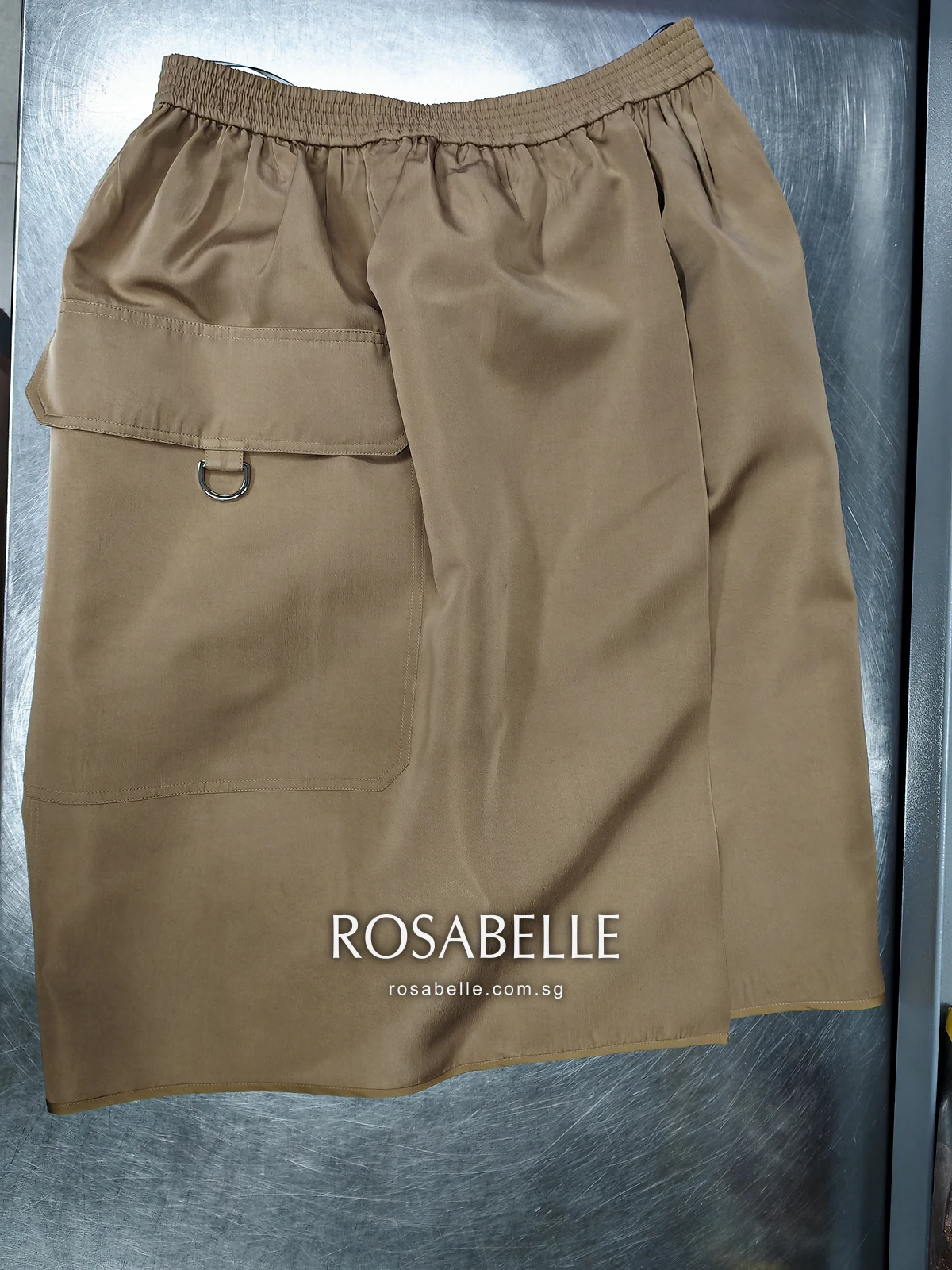 The same camel silk skirt after cleaning, laid flat, the patch pocket and D-ring at the side