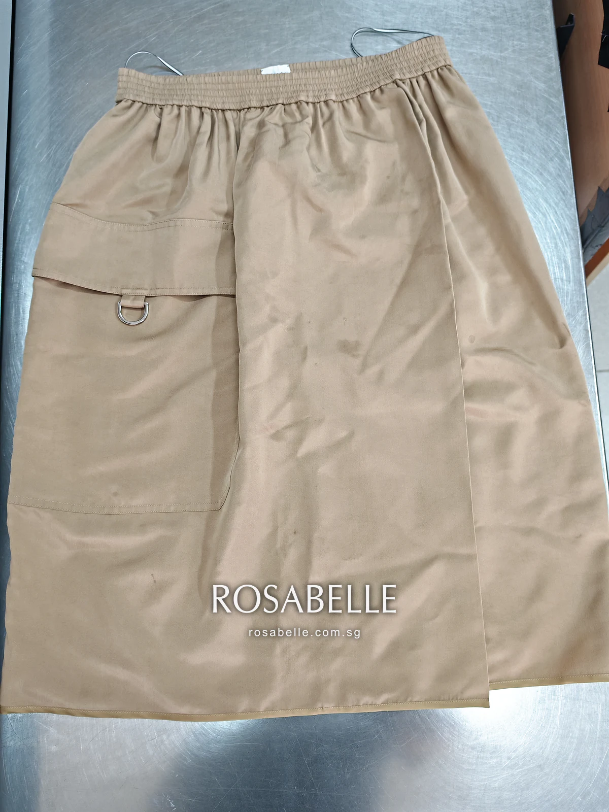 Camel Hermès silk skirt laid flat with an elastic waist and a patch pocket with a D-ring, before food stain removal