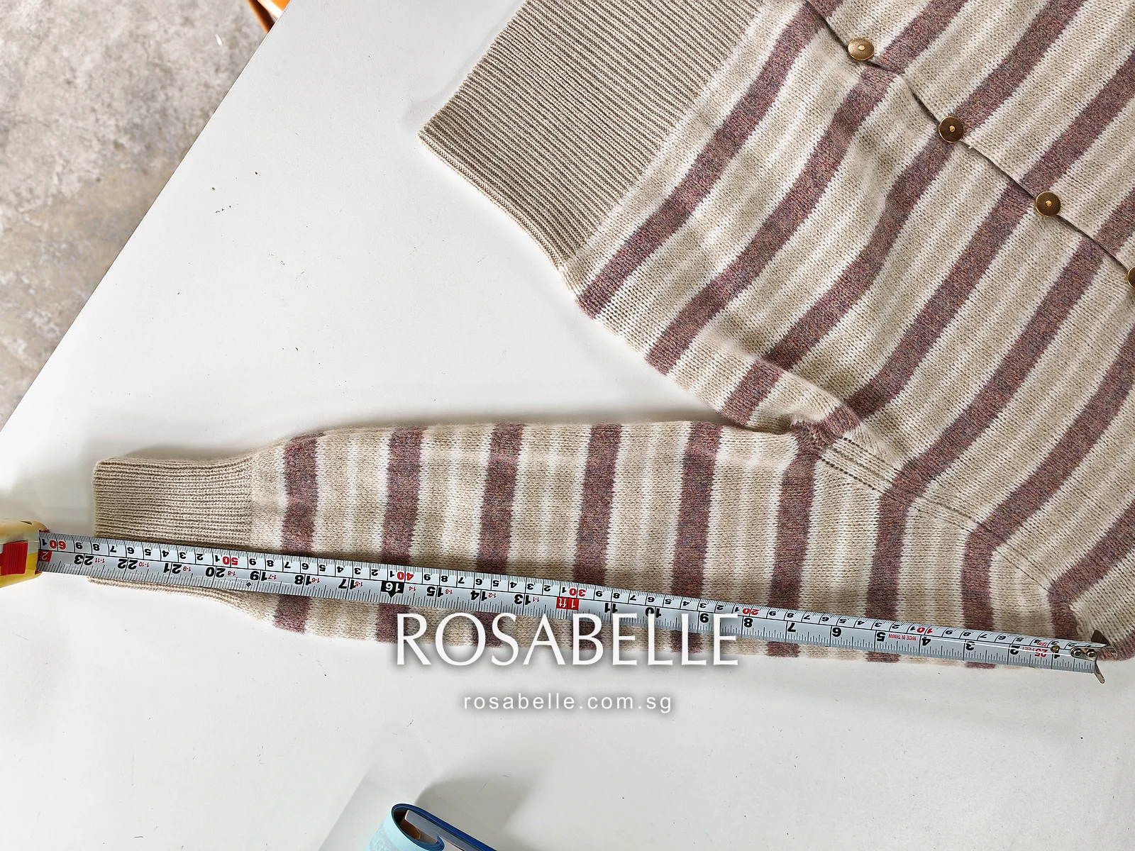 The same sleeve after reblocking, lying straight along the tape with the cuff rib at the end