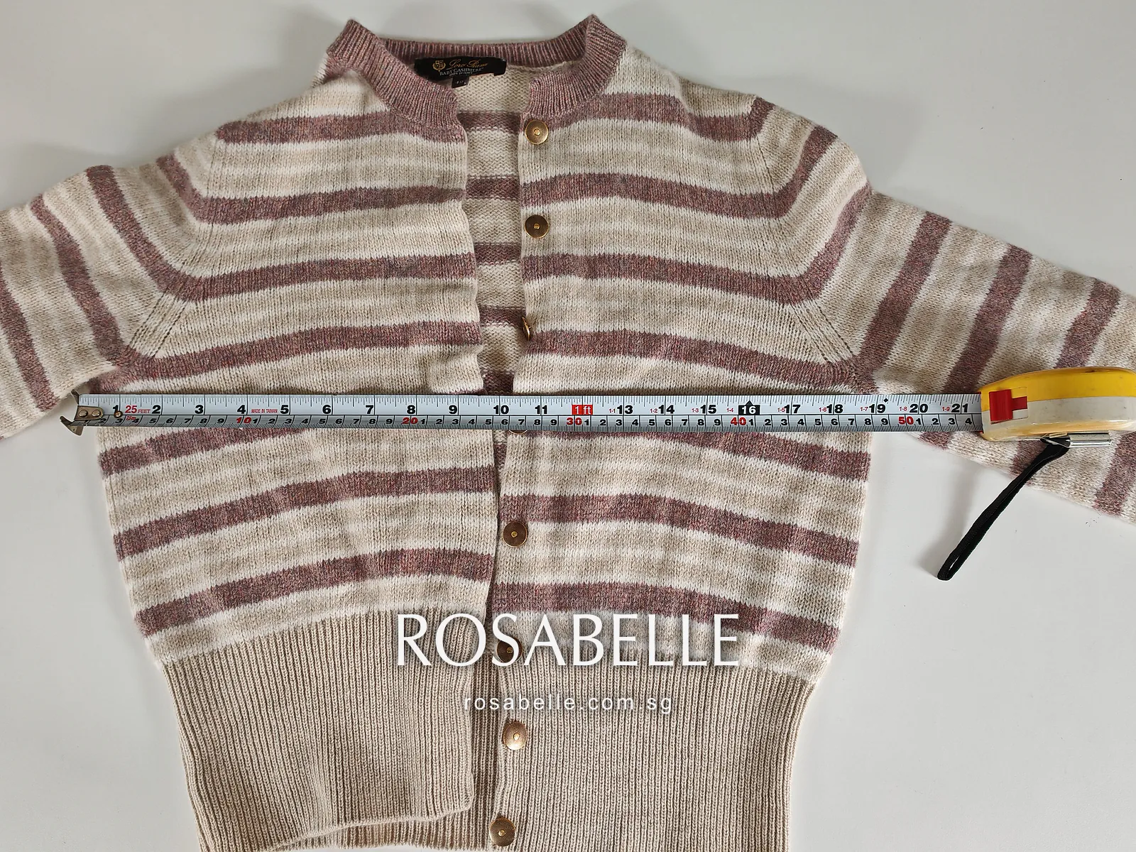 Tape measure laid across the chest of the shrunken cardigan just below the armholes, sleeves folded out to either side