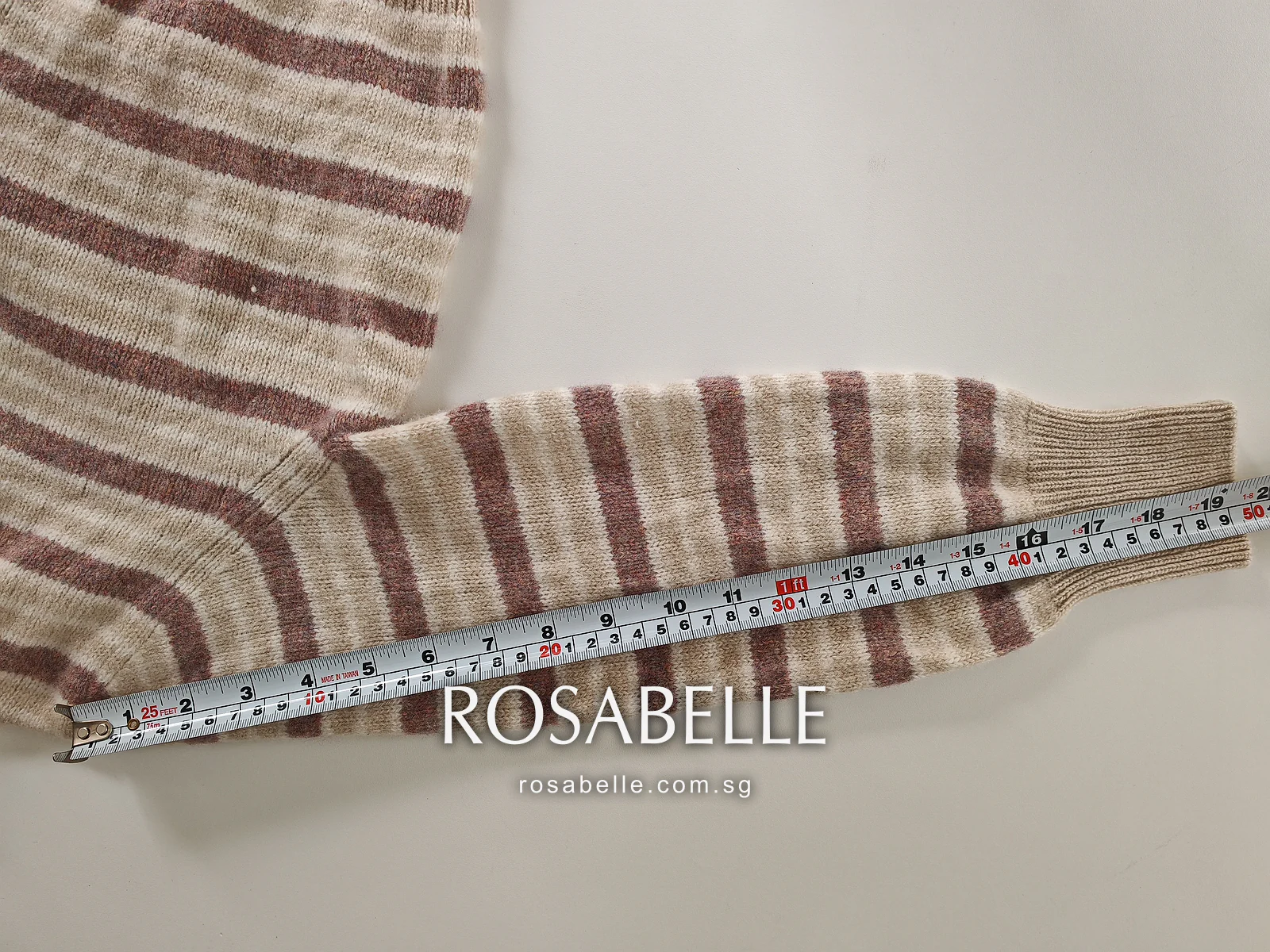Second sleeve of the shrunken cardigan along a tape, buttons of the front placket visible at the top