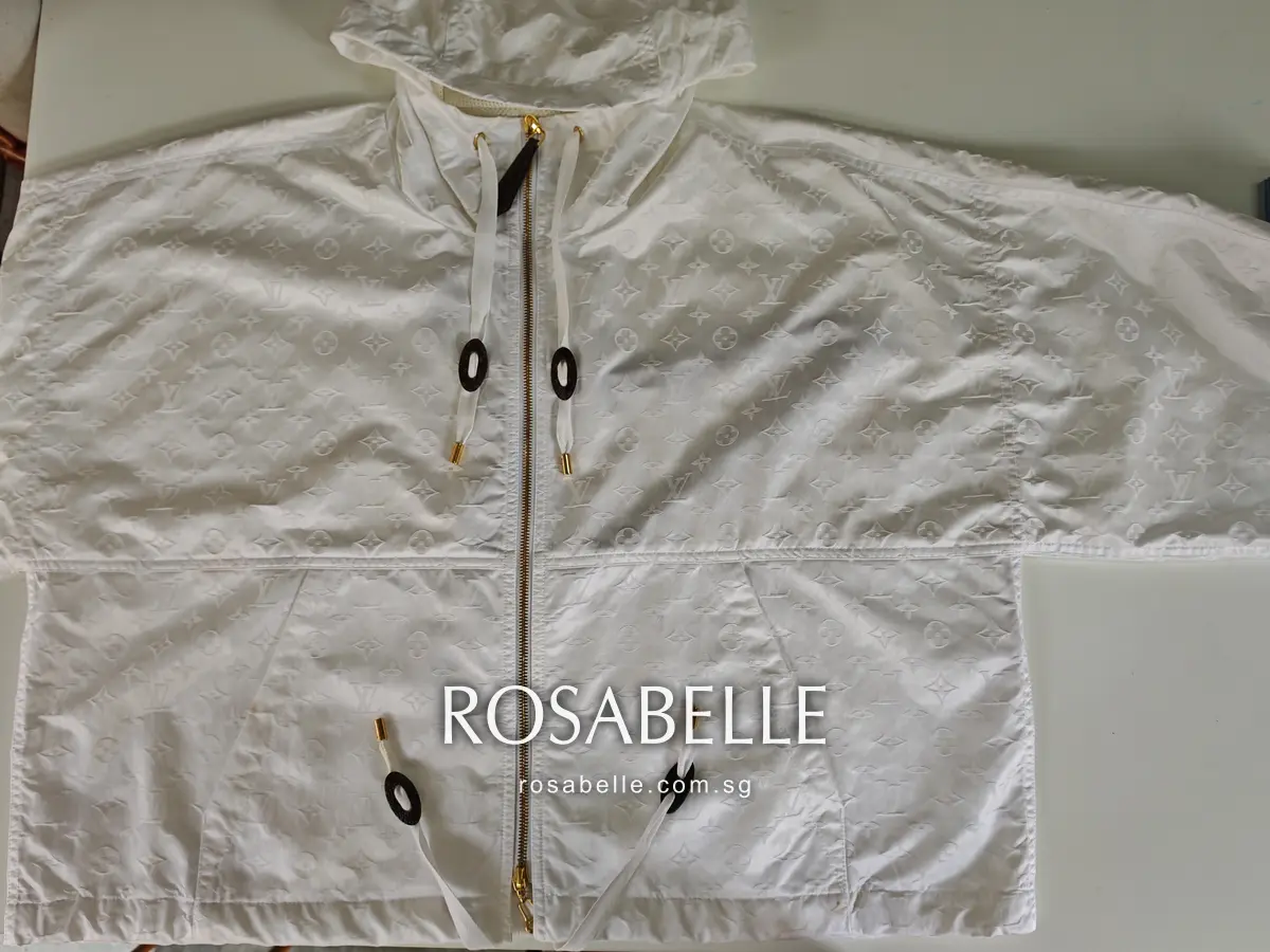 Parka laid flat after cleaning, monogram pattern visible in the white polyamide and oval leather toggles on white cords