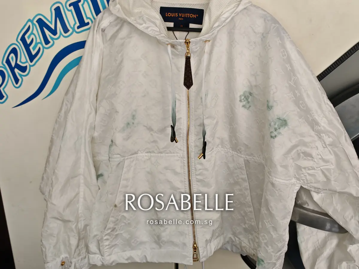 Louis Vuitton parka hanging on arrival, teal dye marks on the chest and the monogram leather zip pull on the zip