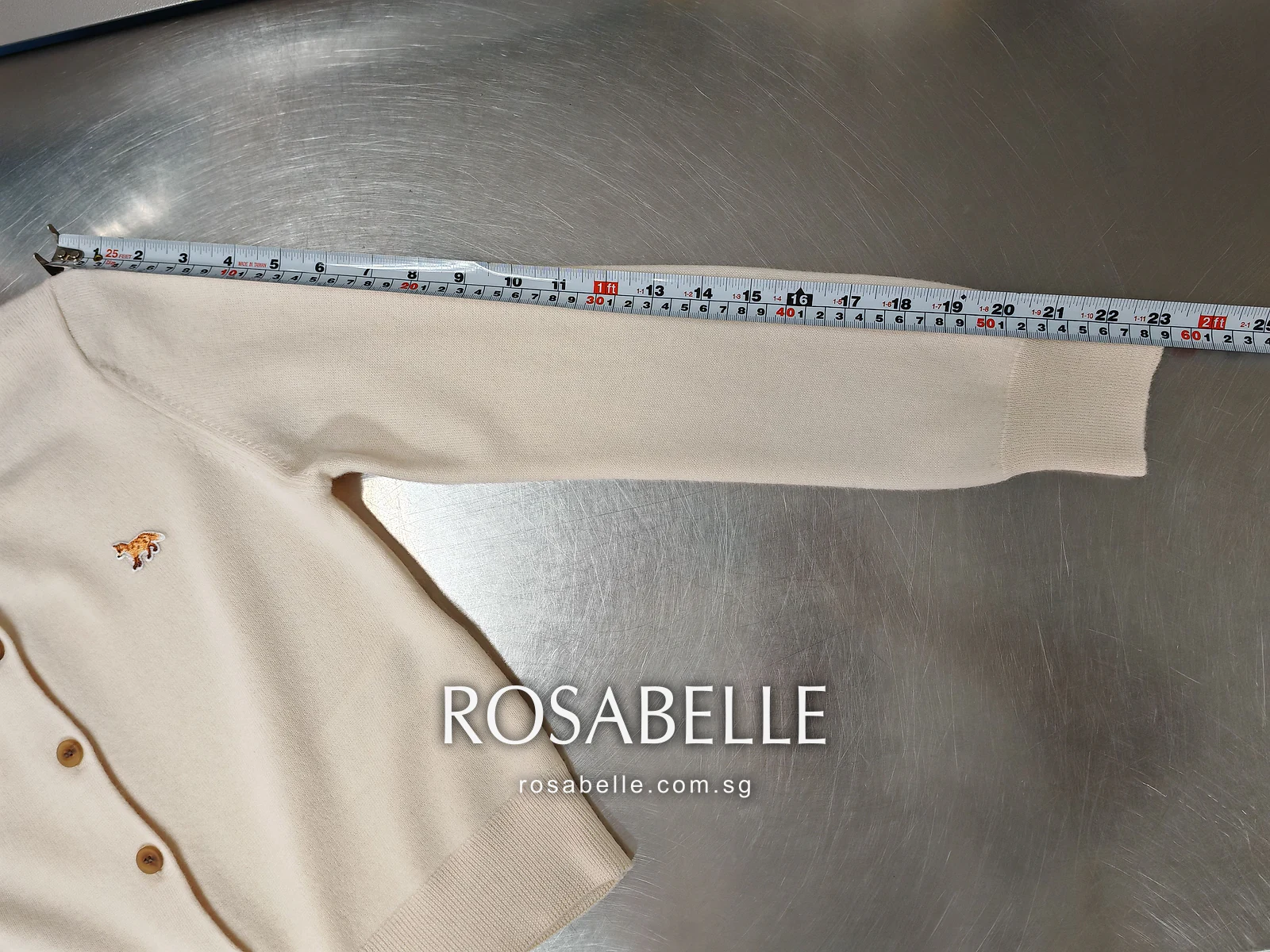 Sleeve of the cardigan after reblocking, measured shoulder to cuff on the steel table with the fox patch in view