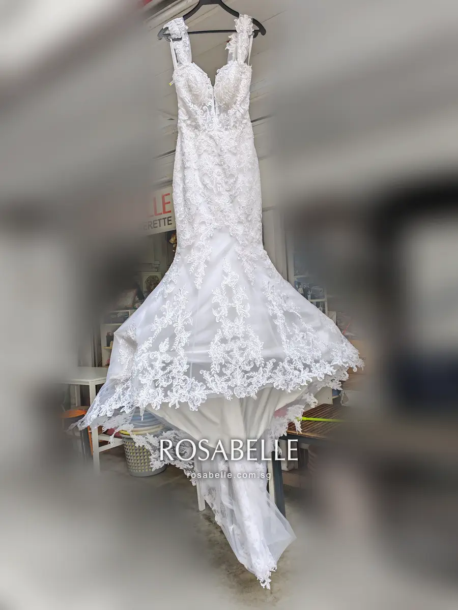 The same mermaid gown after cleaning, hung by its lace straps, the flared lace skirt spread wide over a clean satin underskirt