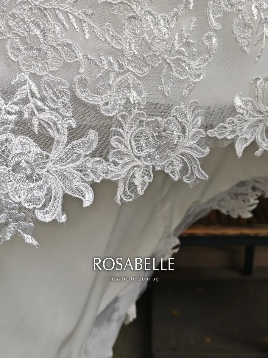 Scalloped lace hem of the gown after cleaning, white floral appliqués with raised cord outlines over the satin