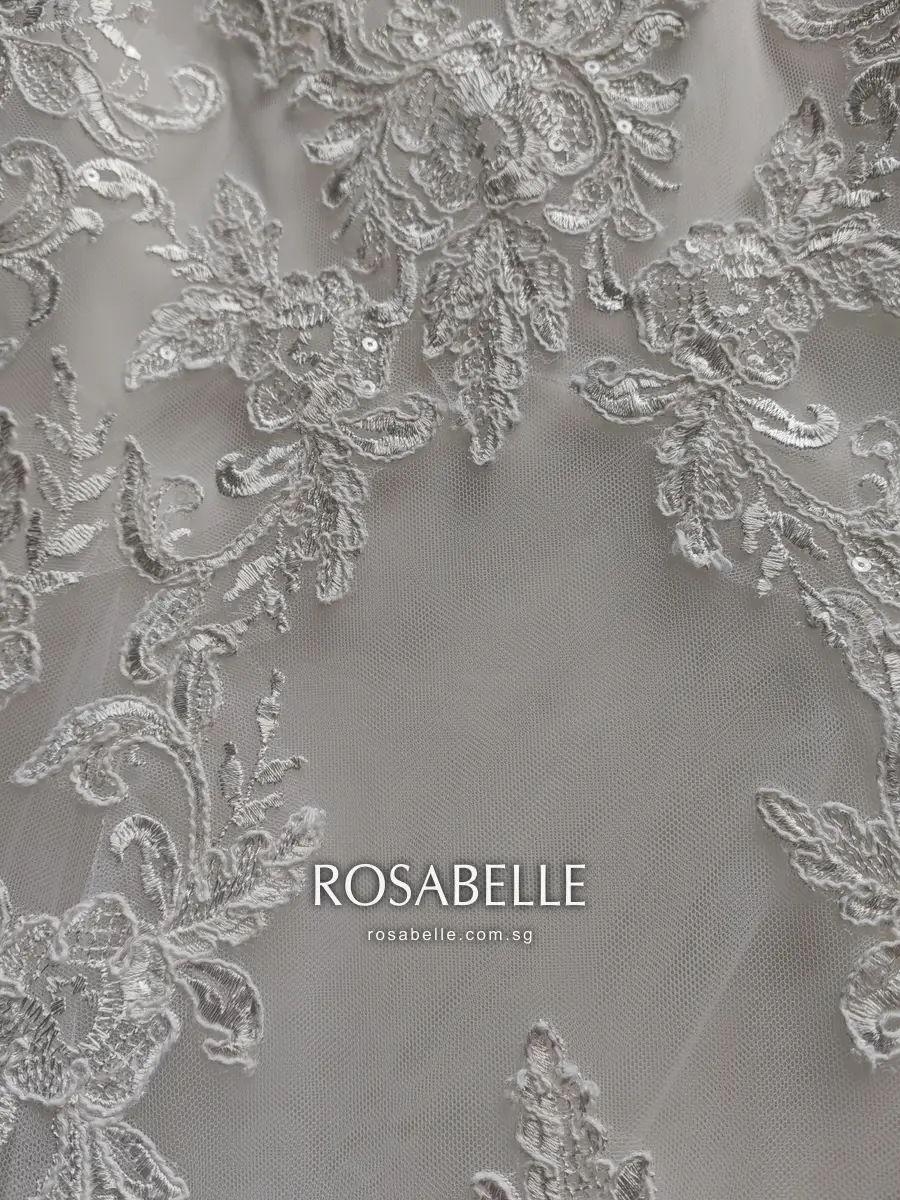 Corded lace motifs with sequins over sheer tulle after cleaning, the embroidery thread an even white with no pink tint