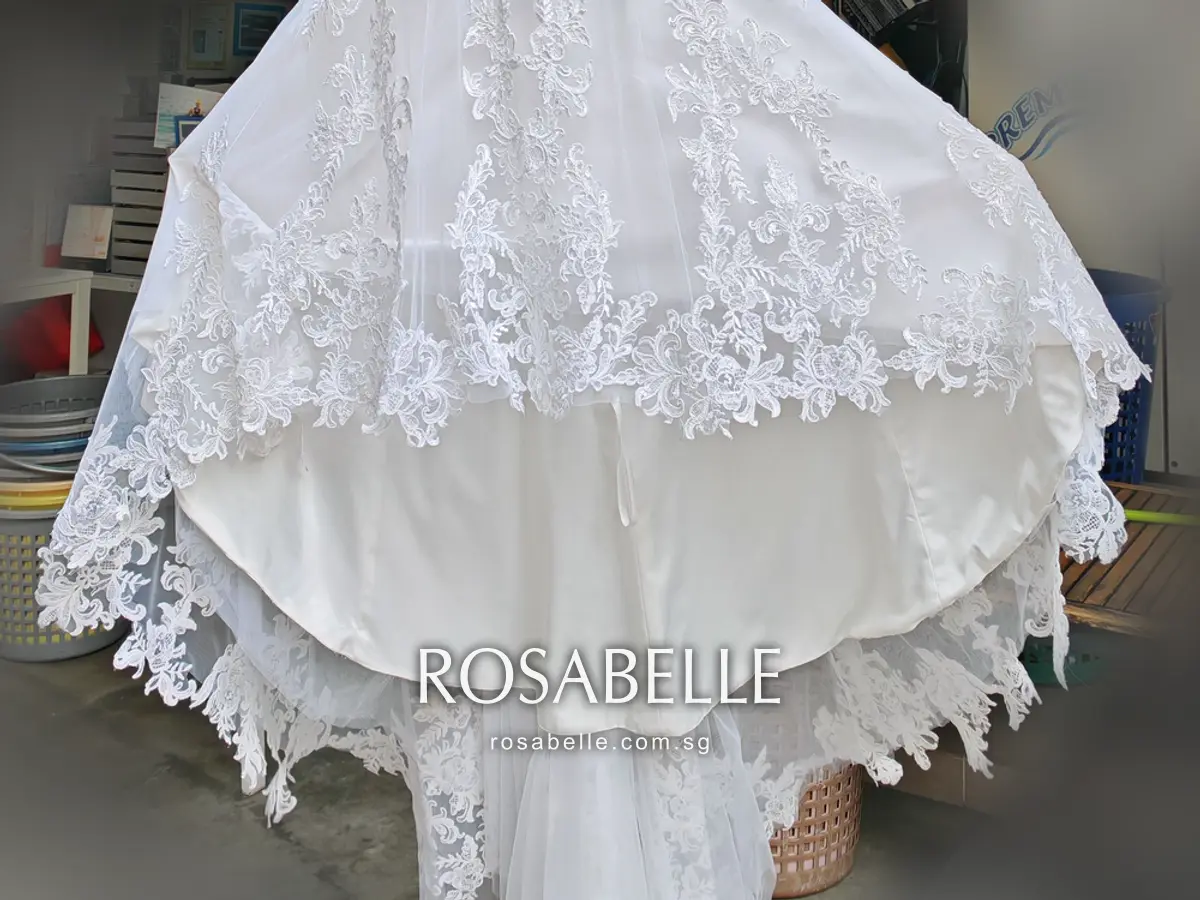 The flare of the gown after cleaning, lace hem above a smooth ivory satin underskirt with tulle and lace trailing below