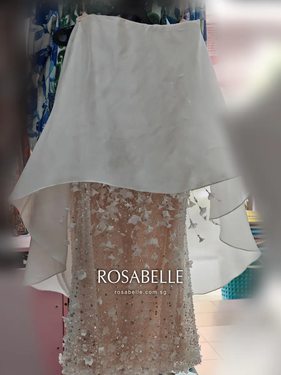 Strapless couture mini dress on a hanger, a white chiffon overlayer falling over a blush beaded skirt