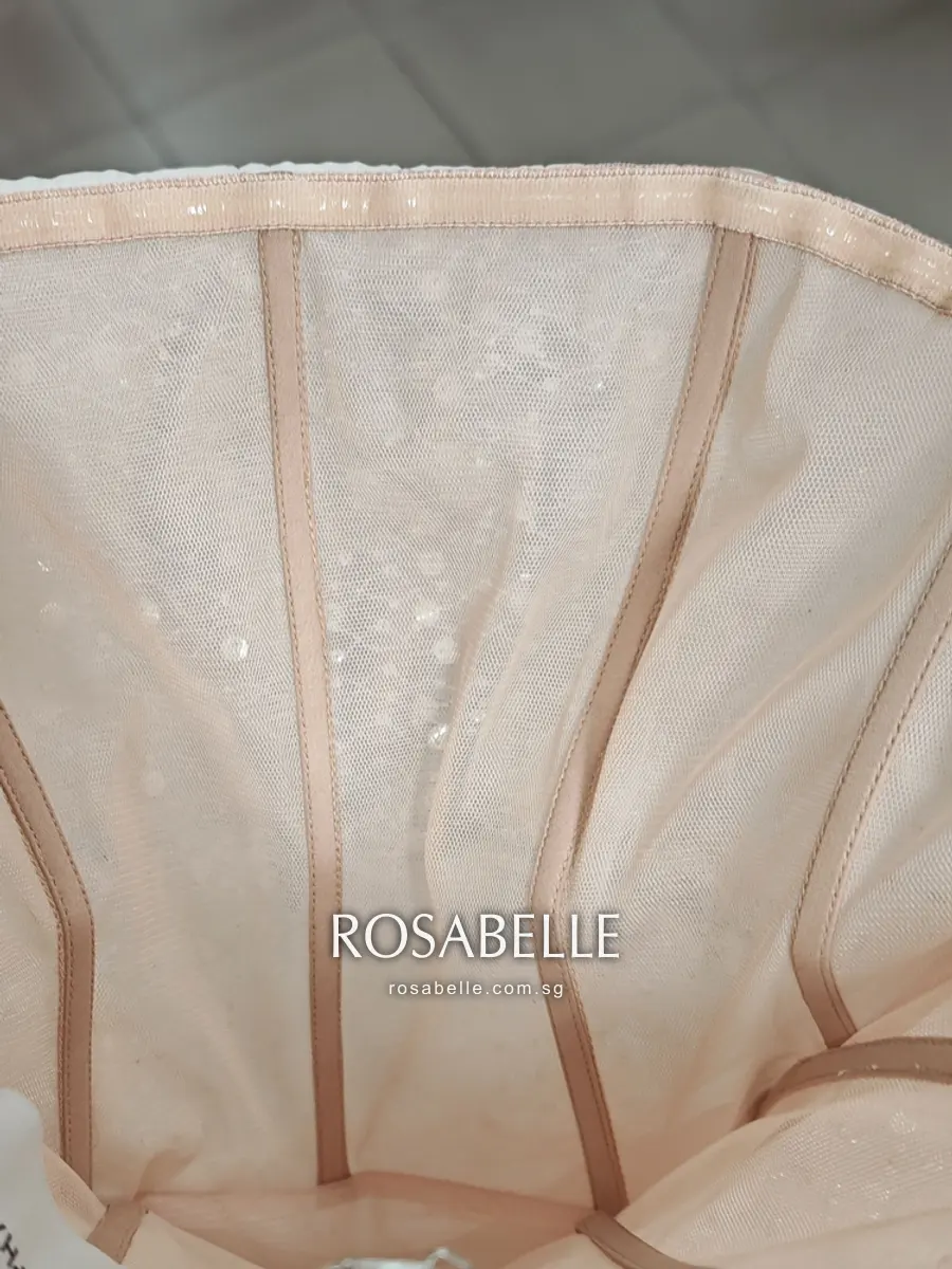 Inside of the strapless bodice showing fine mesh panels divided by vertical boning channels in blush