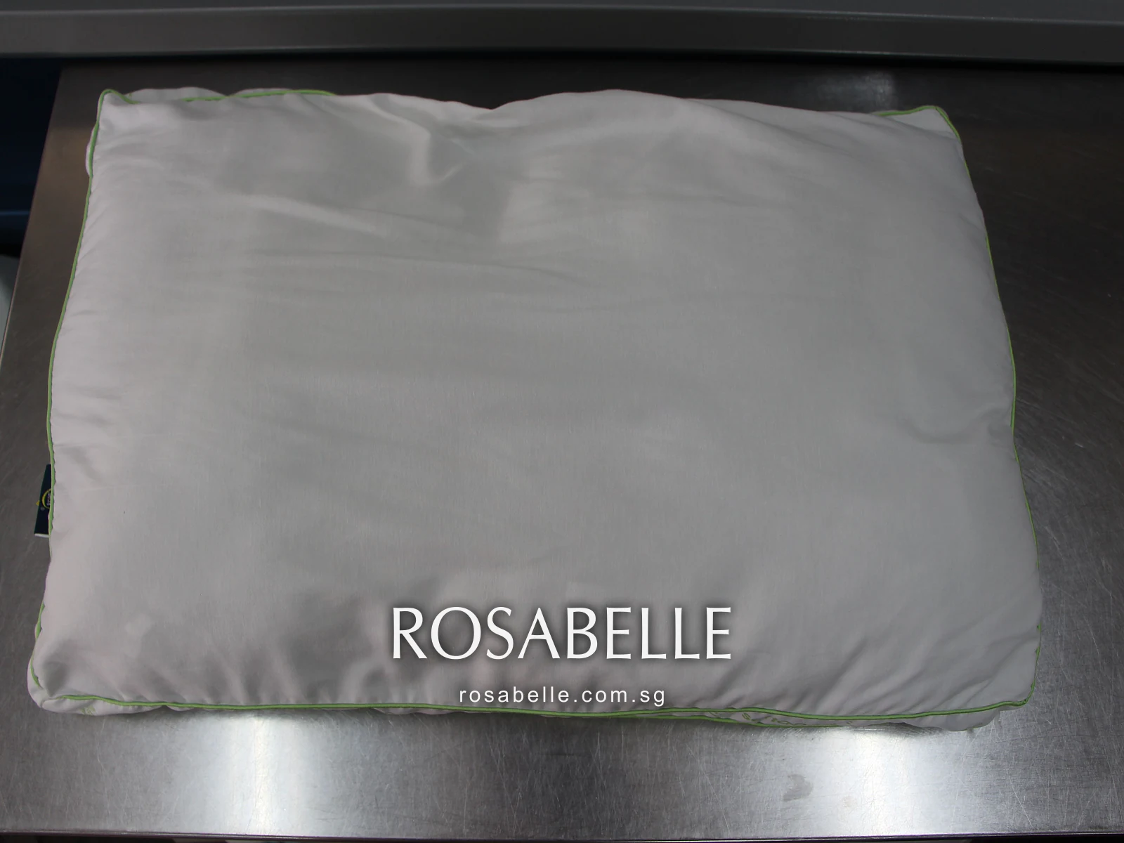 Green-piped pillow after cleaning, white across the whole face, on the steel work table