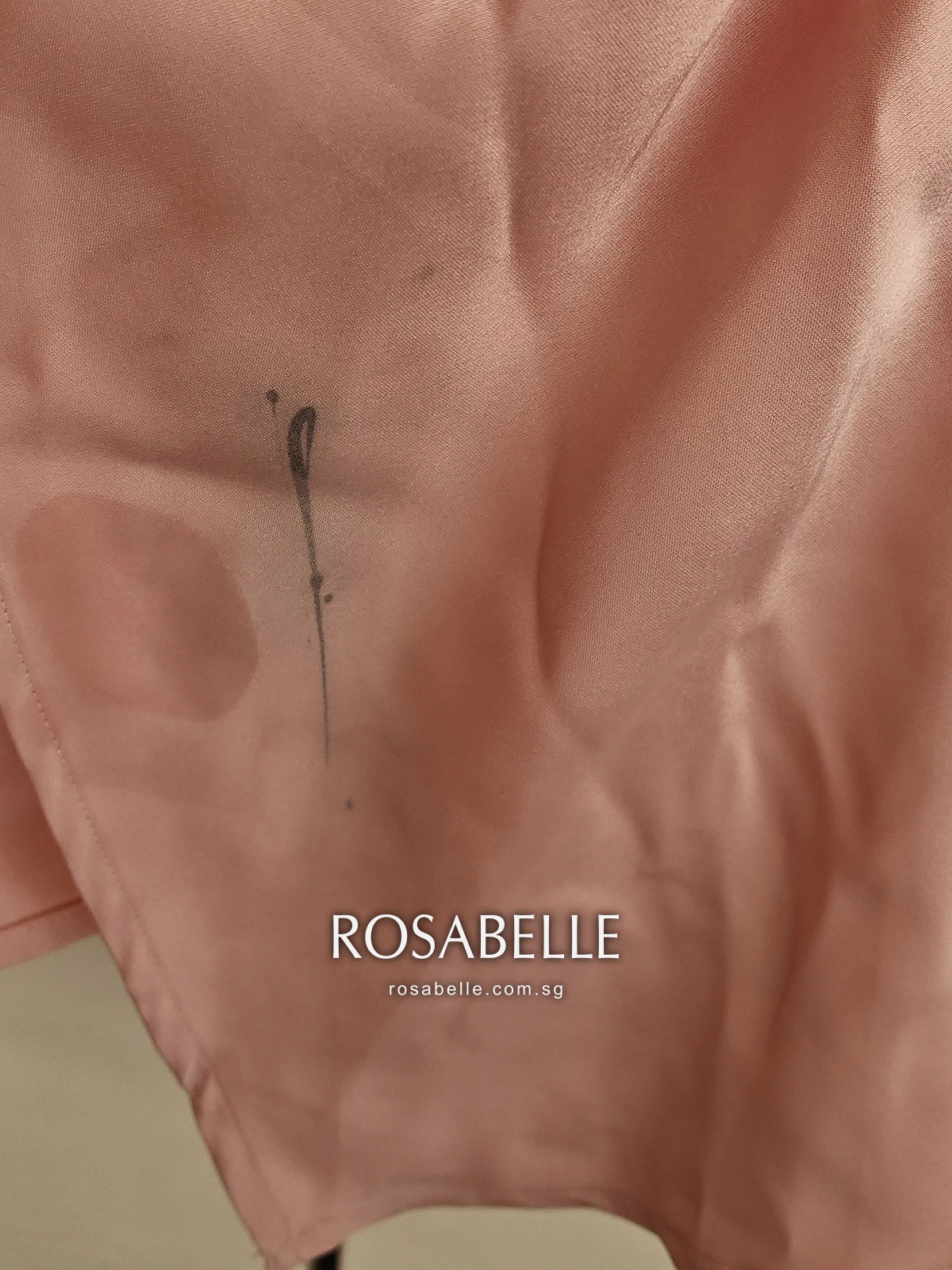 Pink satin skirt panel near the hem with a thin dark grey eyeliner line running down it, before cleaning