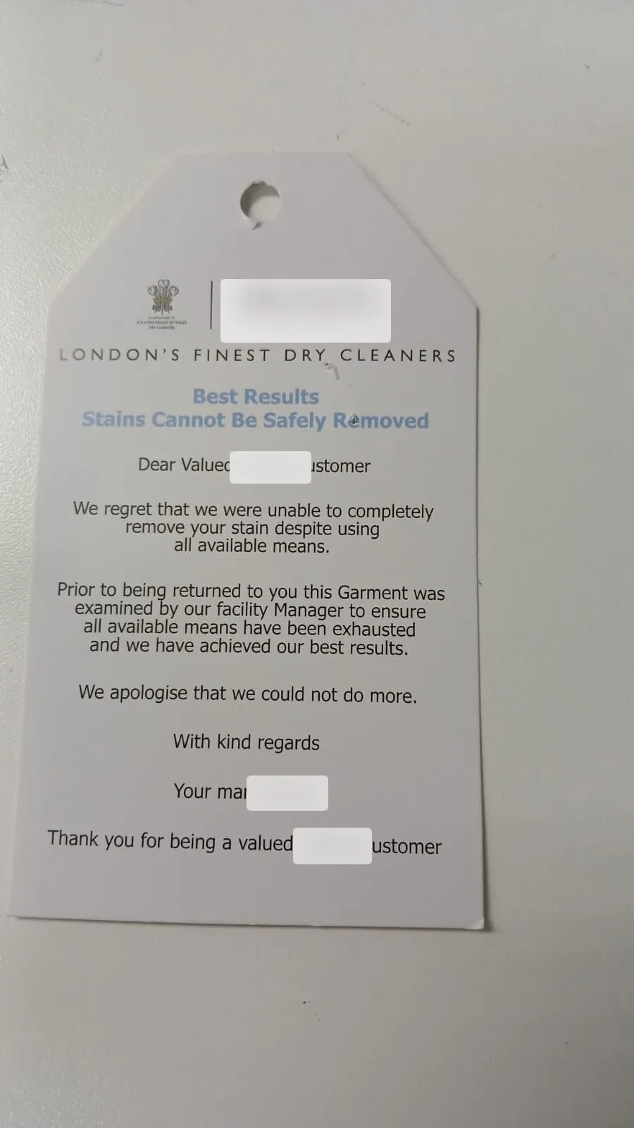 Printed rejection tag from another dry cleaner stating stains cannot be safely removed, identifying details blurred