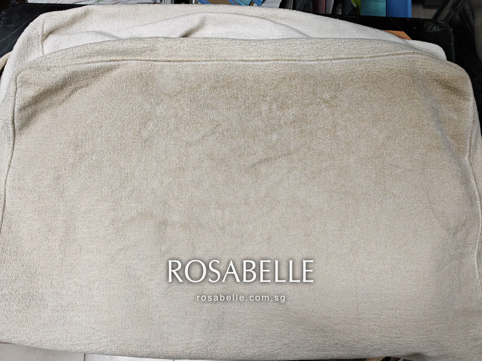 Cream looped-pile sofa cushion cover on its cushion, grey soiling heaviest along one long edge and spreading across the face
