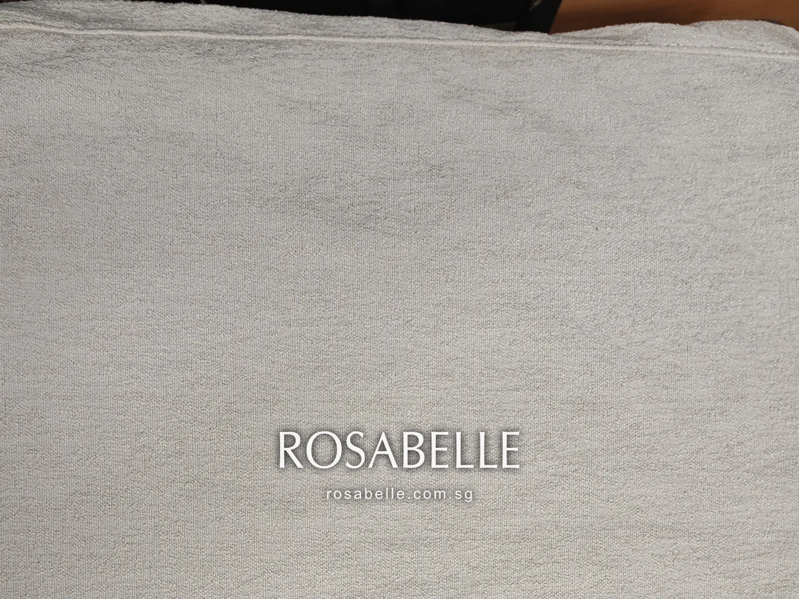 A cream looped-pile cushion cover laid flat after cleaning, its top seam straight and the pile free of lines