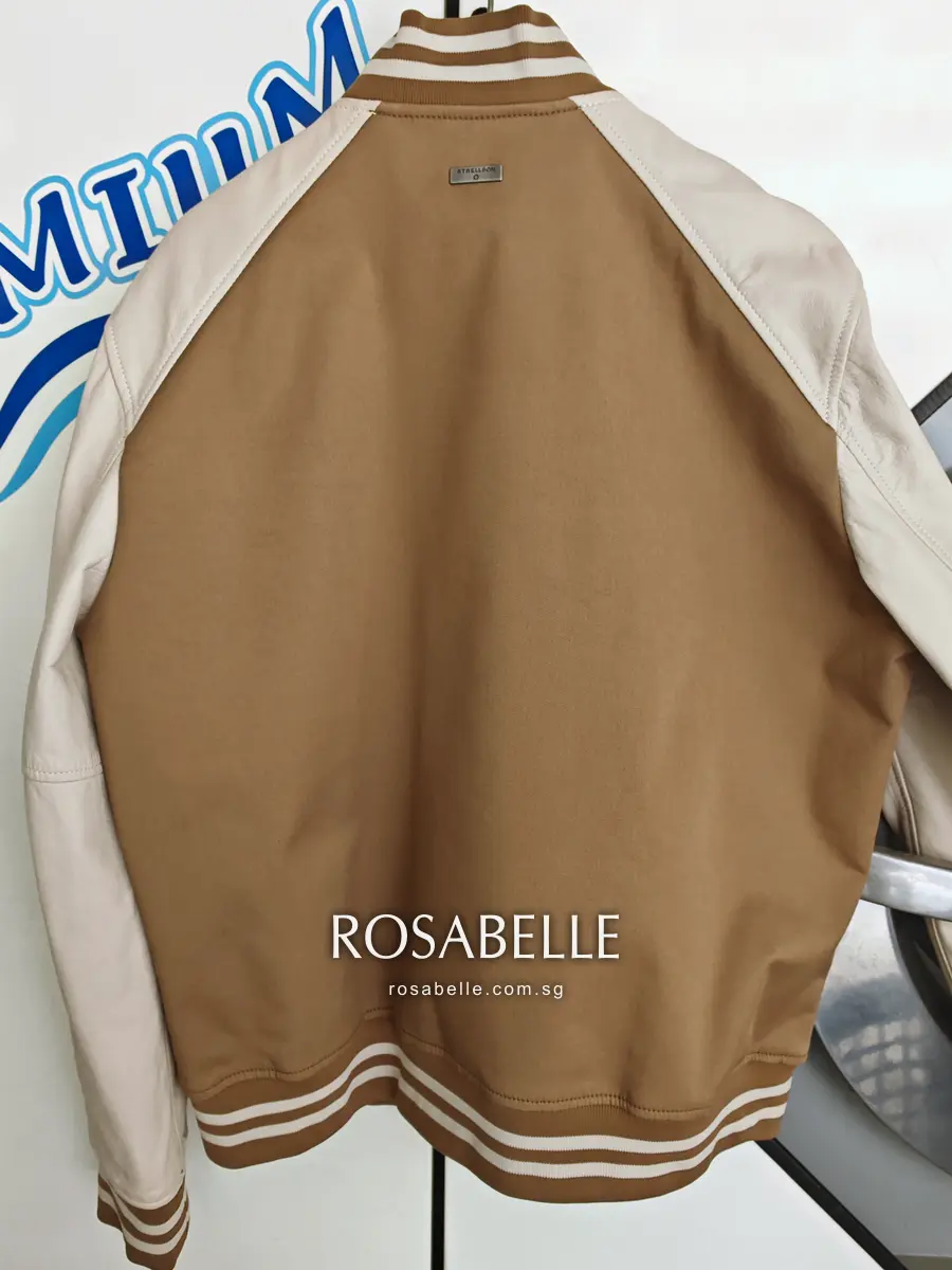 Back view after cleaning, camel body and cream lambskin sleeves meeting cleanly at the seams above a striped rib hem