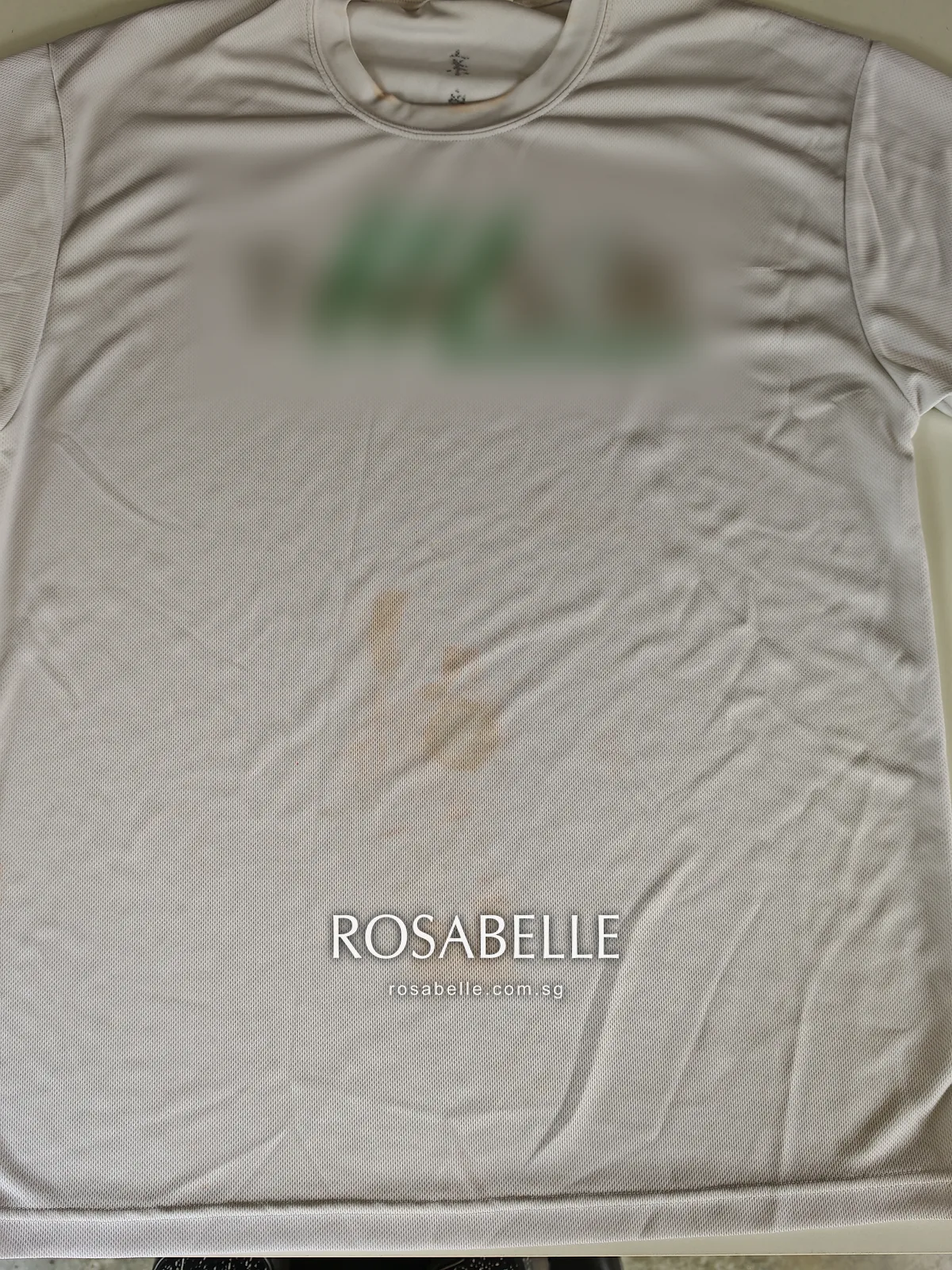 White mesh-knit polyester T-shirt laid flat, brown and orange-brown blotches spread across the lower front