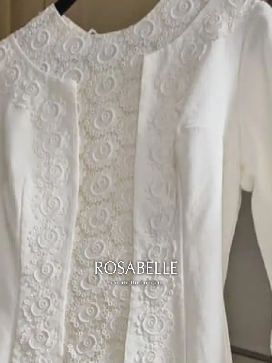 High round neckline above the raised white scrollwork running down the front opening
