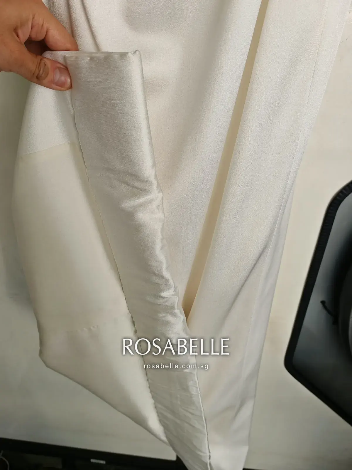 A hand holding the cleaned hem open to show the facing behind it, the brown gone