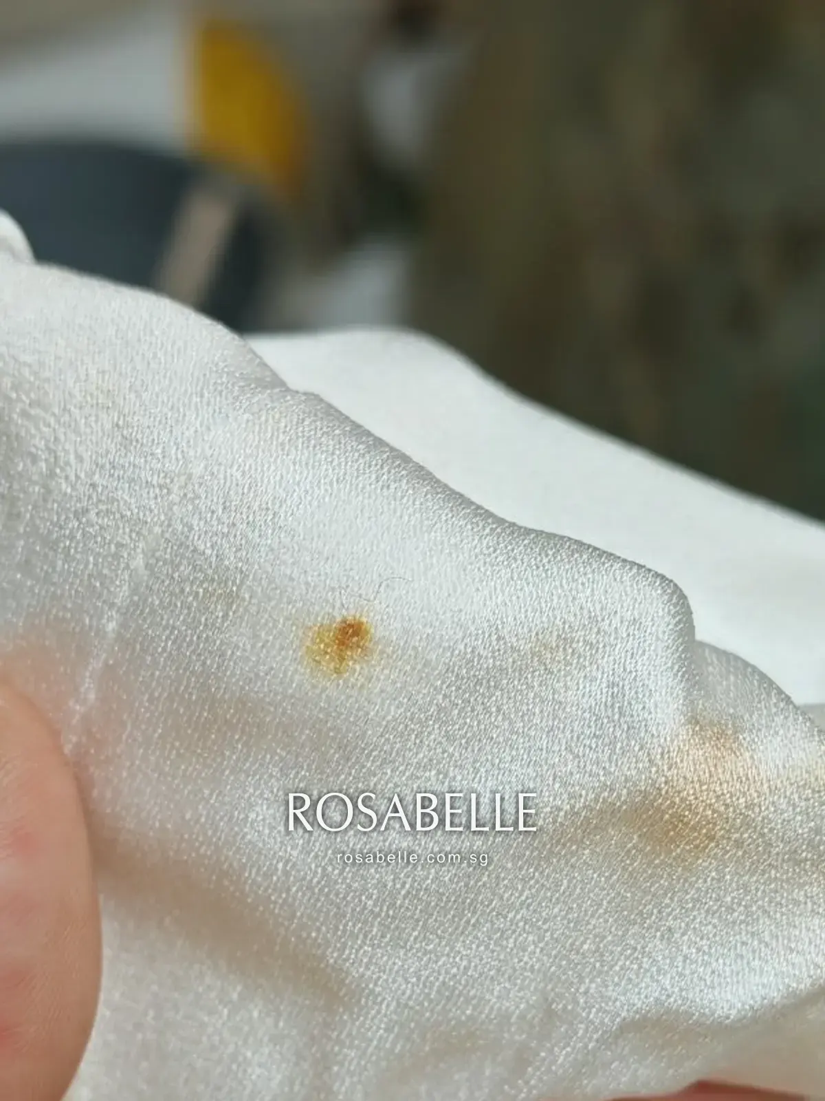 Rust-coloured spotting on the hem edge, a separate problem from the yellowing around it